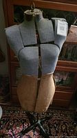Front view of vintage sewing mannequin dress form showing segmented padded torso and beige bottom section with metal stand