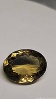 Oval facet cut large champagne citrine gemstone in natural lighting showing brilliance and clarity.