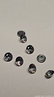 Eight loose calibrated round Mystic Topaz gemstones on neutral background, showing cut and color details.