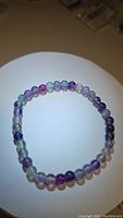 Top-down view of a rainbow fluorite bead stretchy bracelet showing multicolored round beads on elastic string.