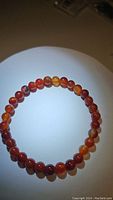 The bracelet laid flat, showing polished round red agate beads on a white background