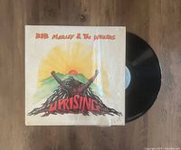 Photo showing the album cover artwork and the vinyl record partially pulled out, placed on a wooden surface.