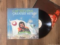 Photo of Cat Stevens Greatest Hits LP Vinyl record partially out of the album cover, showing artwork and vinyl disc