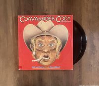 Top view showing red album cover with illustrated surprised man in cowboy hat and two vinyl records partially out of the sleeve.
