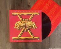 Front view of Commodores Heroes LP vinyl record sleeve with record partially visible along with printed lyric insert.