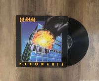 Def Leppard Pyromania vinyl record partially out of its album cover showing the cover artwork and black vinyl surface.