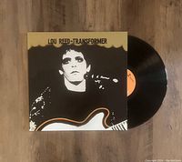 Lou Reed Transformer vinyl LP record partially pulled out from album cover on wooden surface.