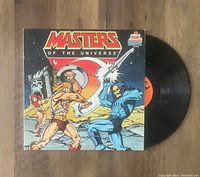 Photo displaying the Masters of the Universe vinyl record LP with illustrated cover of He-Man and Skeletor.