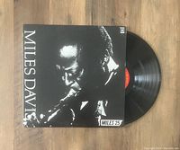 Vinyl record and cover of Miles Davis 'Miles 25' with a black and white close-up photo of Miles Davis playing trumpet.