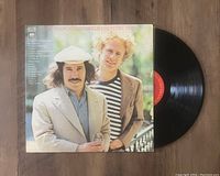 Photo of Simon & Garfunkel Greatest Hits vinyl record partially out of its cover showing the front album artwork with the artists standing outdoors.