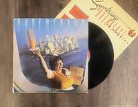 Photo of Supertramp Breakfast In America album cover sleeve with vinyl record partially pulled out, showing front cover art and part of the record disc.