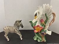 Zebra figurine and swan pitcher side by side showing size and detail.