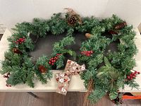 Full 8-foot Christmas garland displayed with pinecones, red berries, and a Santa bow.