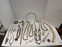 Overview of assorted costume jewelry necklaces and some bracelets arranged on a tray, showing varied styles and colors.