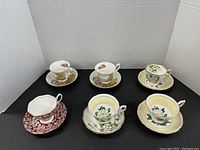 Photo showing six bone china teacups and six matching saucers from above and side, showcasing the floral and gold trim designs.