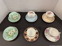 Overview of all six cup and saucer sets arranged on black background