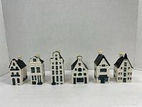 Front view of all six ceramic Delft blue houses arranged in a row against a white background.