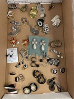 Tray with assorted earrings featuring silver-tone, gold-tone, red flower designs, hoops, and studs