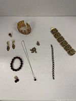 Overview of entire jewelry lot showing bracelets, earrings, necklace, and pendants.