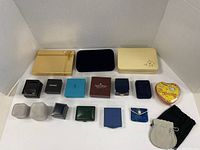 Full view of all 16 assorted jewelry boxes and pouches arranged on white background.