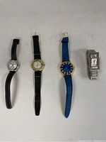Four ladies watches laid out showing the full length including straps and faces
