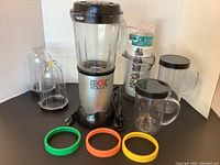 Magic Bullet blender base with large pitcher jar, two smaller jars with lids, blade assembly, and three silicone rings