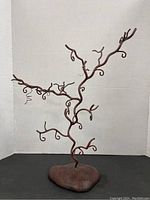 Full view of metal branch tree sculpture with curving twisted branches on a textured base