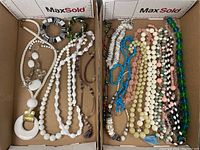Two trays containing multiple long beaded necklaces of various colors and styles.