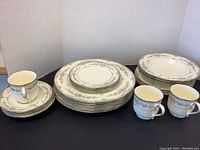 Full set elements including stacked plates, bowls, cups with saucers arranged on a black background showing entire lot.