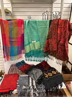Full view of all 8 scarves including hanging and folded scarves showing various colors and patterns.