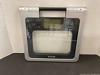 Front view of Taylor digital glass bathroom scale showing clear platform and digital display in center.