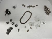 Full lot laid out showing bracelet charms, necklace, earrings, flower pins and accessories