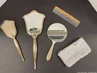 Top angle view of entire set showing all items: brush, hand mirror, round mirror, comb and sequin purse.