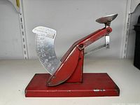 Red vintage egg scale with numeric dial and metal bowl, showing impairment of bowl shape