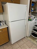 Closed view of white GE top-freezer refrigerator showing overall shape and exterior condition.