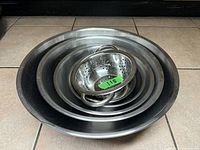 Photo showing all stainless steel mixing bowls nested together with the strainer in the center on tiled floor