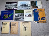 Overview of 11 books and pamphlets on Hamilton history and events laid on carpet