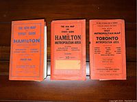 Three folded orange booklets for Hamilton 1951 and 1956 maps and a 1957 Toronto map.