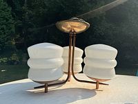 Front view of the three-arm fixture set outdoors showing metal canopy, curved arms and glass shades