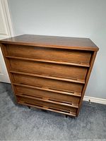 Front full view of walnut highboy dresser showing five drawers, integrated pulls and tapered legs