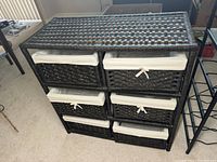 Front view of wicker storage unit with six drawers and white fabric liners.