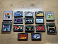 Overview of all Nintendo game cartridges laid out on wooden surface showing the full lot of 16 game cartridges.