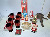 Wide shot showing all items in lot including candle holders, figurines, tree toppers, miniature tree, string lights, and cast iron stand.