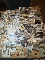 Wide view of numerous postcards spread out on table showing a variety of images including animals, landscapes, buildings, and holiday themes.