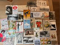 Overview of the entire collection of vintage postcards and ephemera showing a variety of black and white and colored items with scenes, people, advertisements, and animals.
