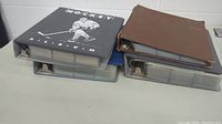 Four ring binders stacked, three horizontally on bottom layer and one on top, one labeled 'Hockey Album'