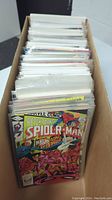 Photo of long box containing neatly packed comic books in plastic sleeves, identifiable Spider-Man cover at front.