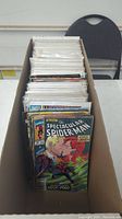 Photo showing a long box filled with comic books organized mostly in protective sleeves, visible top-down view of the comics