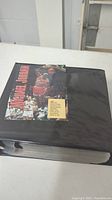Black large binder with a cover page featuring Michael Jordan in action with text, contains plastic sleeves filled with basketball cards.