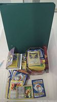 Binder and two cases with loose Pokémon cards, cards include Zapdos holo, some cards with visible edge wear